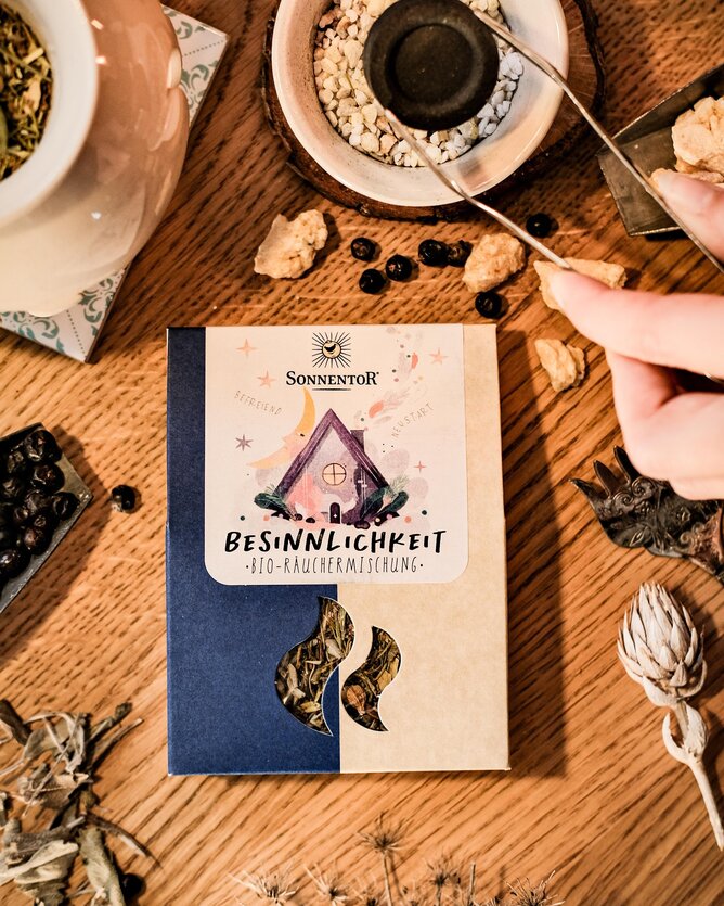 Photo of a pack of incense blend Besinnlichkeit. Next to it you can see how just smoked. | © SONNENTOR